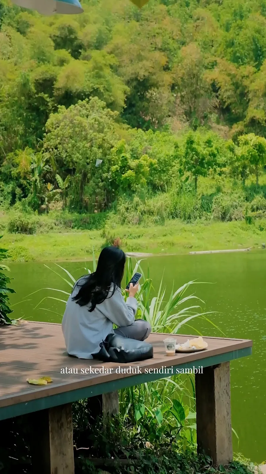 Pengunjung duduk sendiri di dek tepi danau